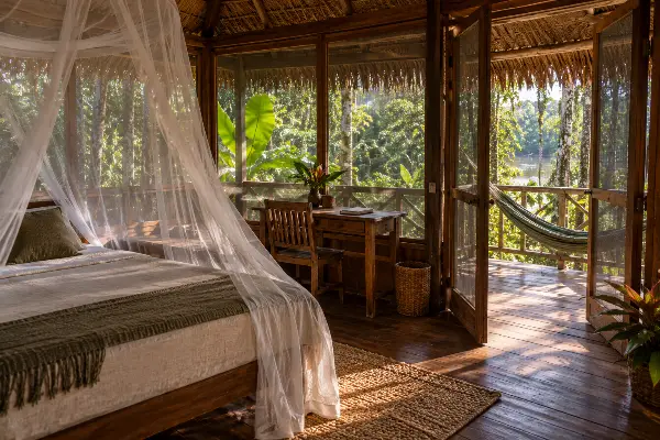 Private guest tambo with a mosquito-netted bed and writing desk at a 10-day ayahuasca retreat in Peru