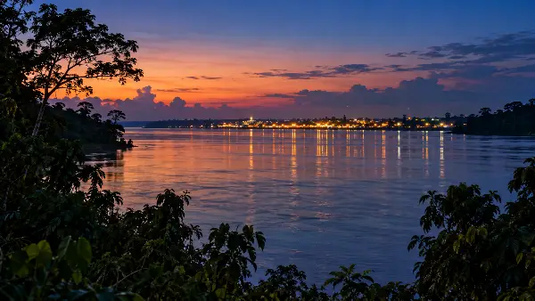 City lights far across an Amazon river at dusk, the 45 to 90 minute boat trip to a hospital in pregnancy