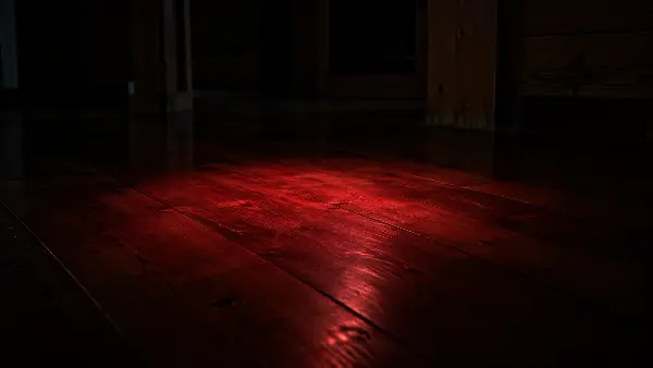 Red headlamp light on a dark maloca floor, the light a facilitator brings to your mat during an ayahuasca ceremony